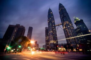 Gambar menunjukkan Menara Berkembar Petronas yang megah di Kuala Lumpur sewaktu malam. Lampu - lampu di bangunan - bangunan itu berseri - seri, manakala jalan raya penuh dengan sinar - sinar kilas balas kenderaan. Ramalan Pemasaran Media Sosial di Malaysia 2025: Bentangan kota ini dengan landmark ternama Malaysia boleh menjadi inspirasi untuk strategi pemasaran media sosial. Potensi untuk menggunakan imej like ini untuk menarik minat pengguna media sosial semakin besar menjelang 2025.