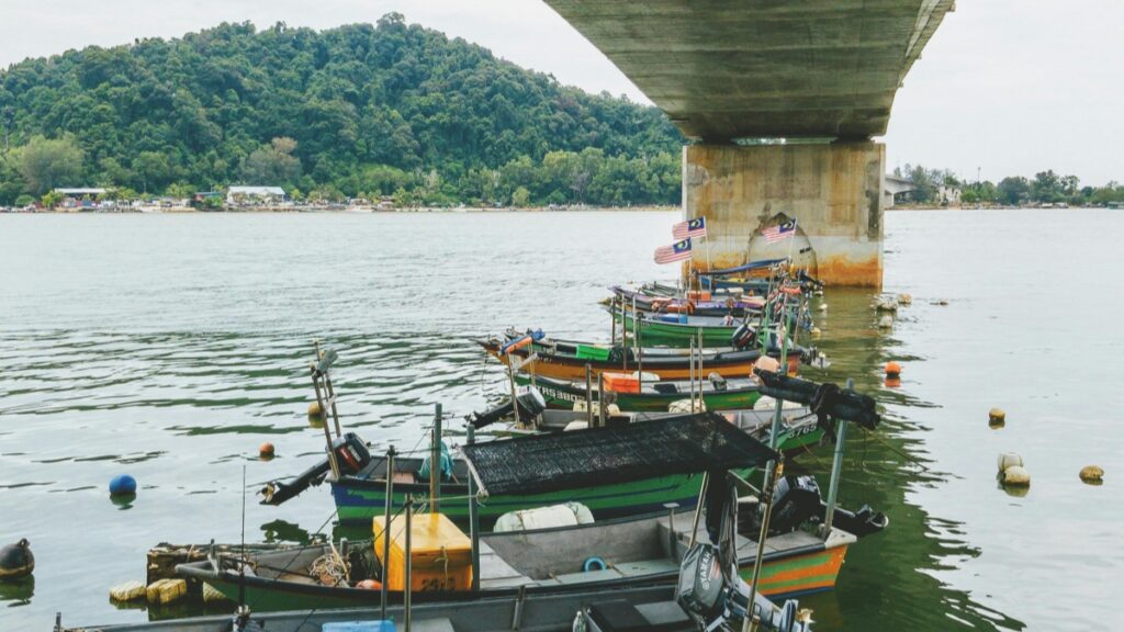 Gambar menunjukkan beberapa bot nelayan yang diparkir di bawah jembatan di tasik,dengan pemandangan bukit yang menutup latar belakang."Cara Menjana Wang di Bigo Live"adalah topik yang sering dibincangkan oleh mereka yang mencari cara untuk menghasilkan pendapatan melalui platform streaming live.